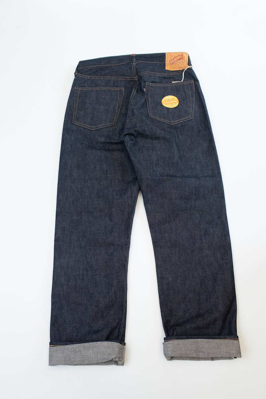 Pair of dark blue jeans with a brand label on a white background