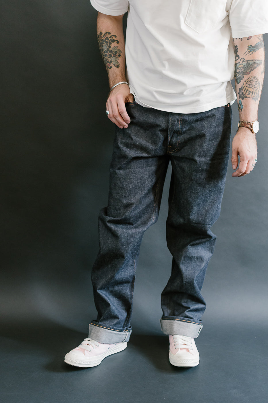 Person wearing dark jeans and a white shirt against a dark background