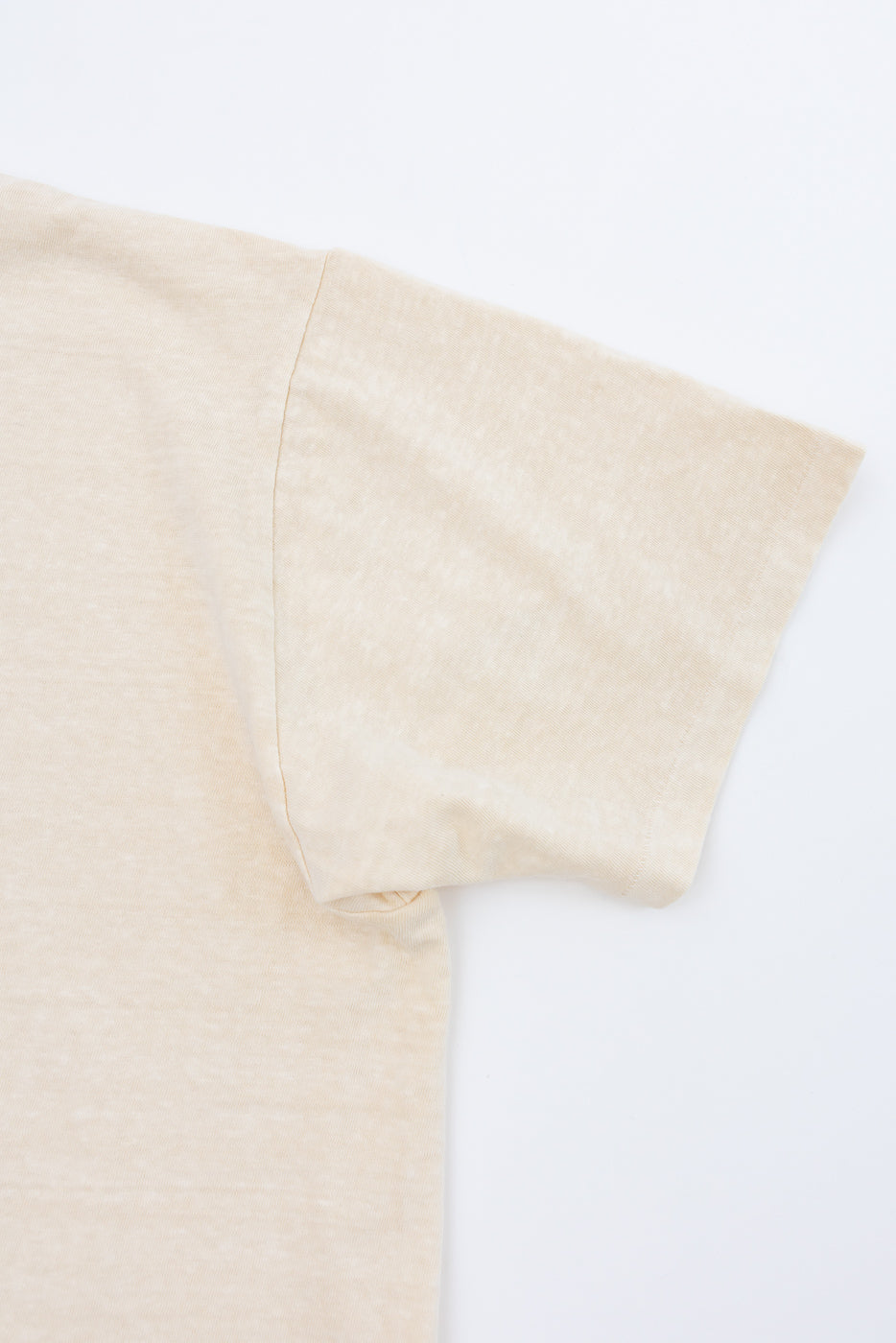 Close-up of beige t-shirt sleeve, showing fabric texture and hem detail