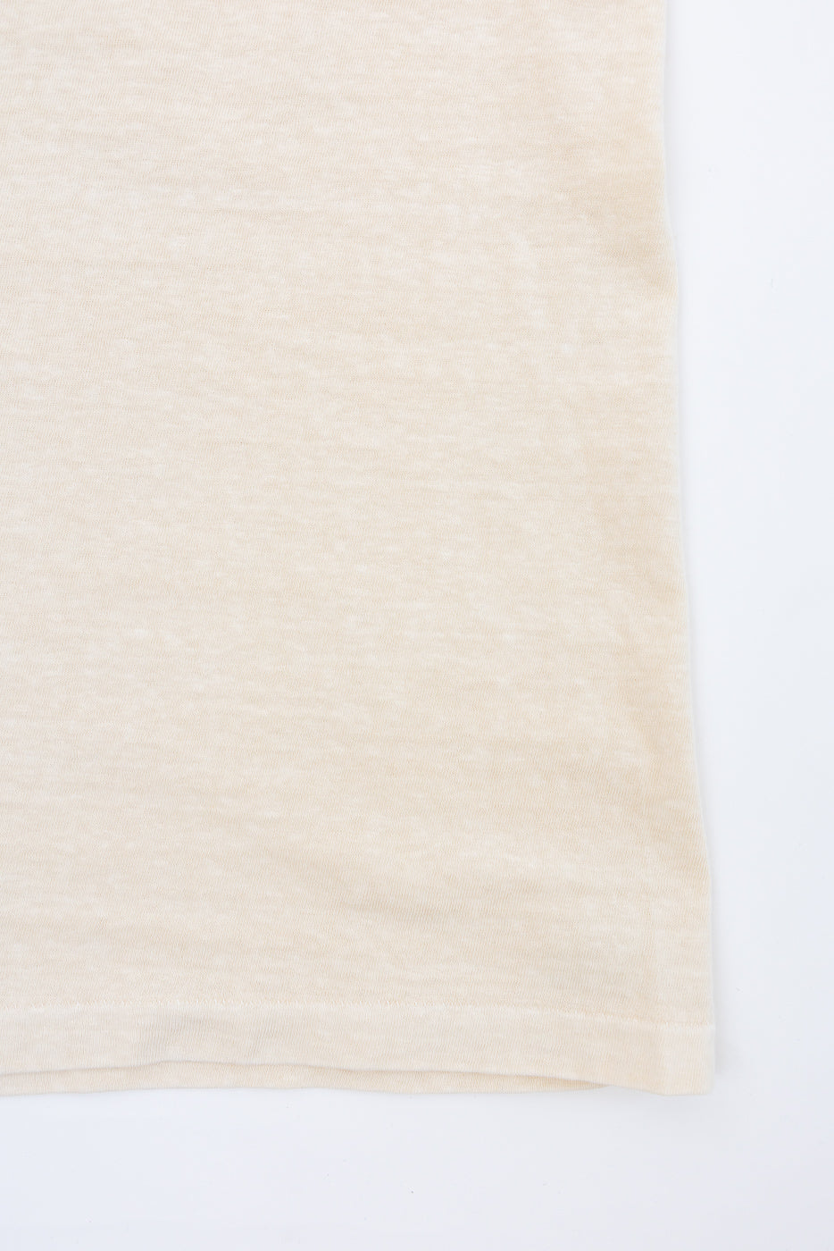 Close-up of beige t-shirt hem, front view, showing fine knit texture and clean stitching detail
