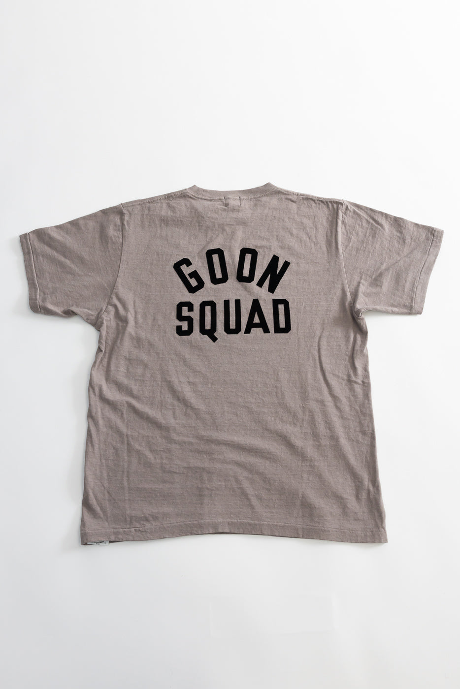 The 5.4oz Raffy Tenjiku Printed T-Shirt Ski Inn in grey features GOON SQUAD in bold black letters on its back, highlighting its vintage-inspired, seamless tubular design.