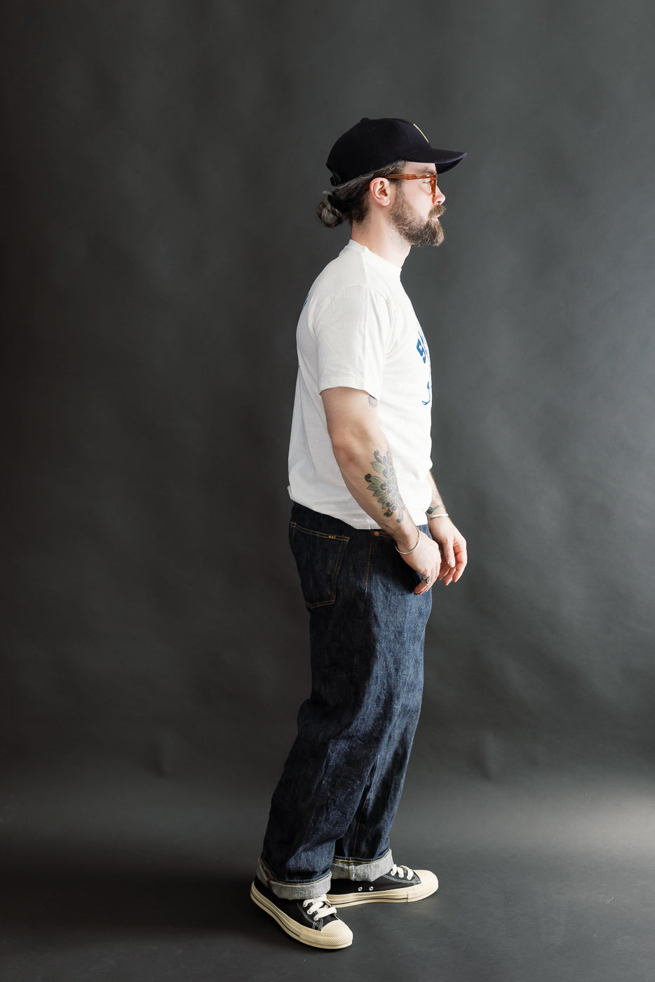 Man in profile models the 5.4oz Raffy Tenjiku Printed T-Shirt Ski Inn - Off White, showcasing its vintage-inspired tubular knit design and slub jersey texture.