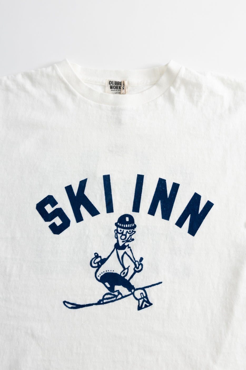 5.4oz Raffy Tenjiku Printed T-Shirt Ski Inn - Off White, features SKI INN text with a skier cartoon; crafted from slub jersey cotton, showcasing a vintage-inspired tubular design without side seams.