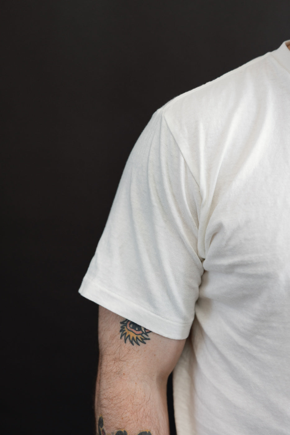 Close-up side view of a white t-shirt sleeve on a male model, 5'9