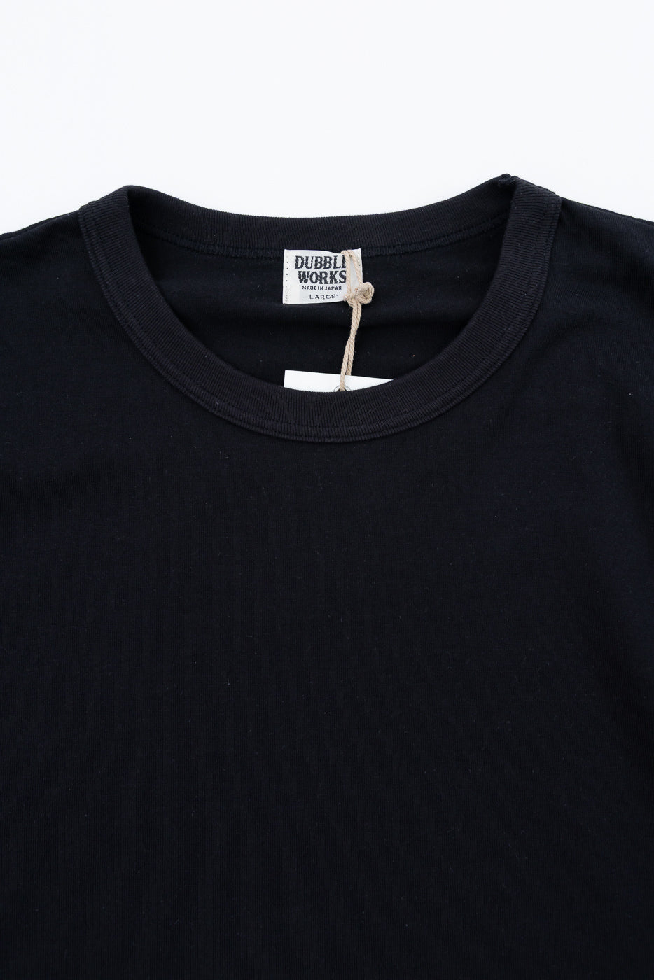 Close-up front view of black t-shirt collar with Dubble Works tag, showcasing fabric texture and label details.