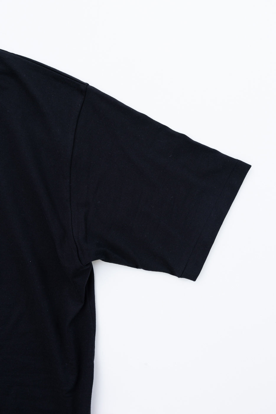 Black t-shirt sleeve close-up showing ribbed hem and shoulder seam detail, front view
