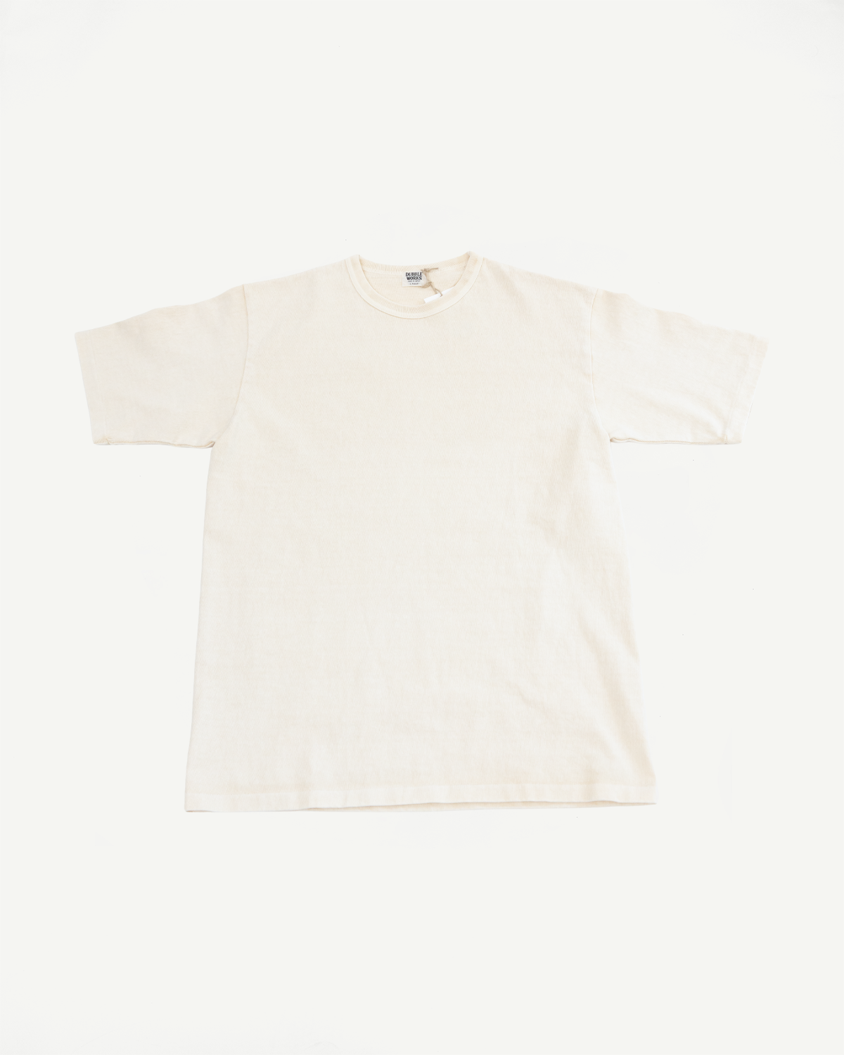 Front flat lay of cream cotton tee with ribbed collar and tag detail