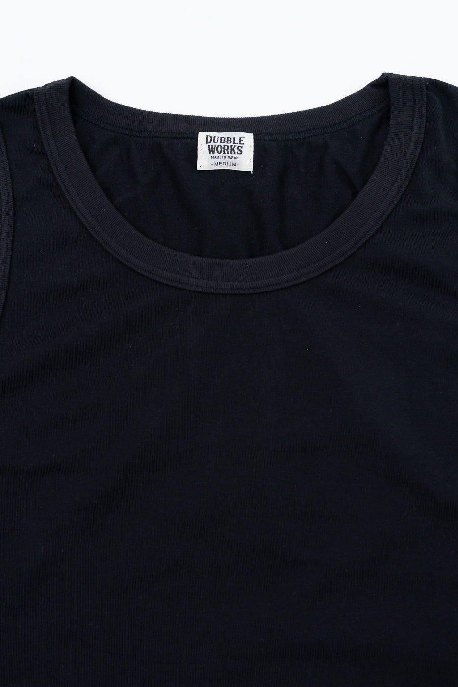 Close-up of black tank top front, showing ribbed crew neck and Dubble Works tag, size medium.