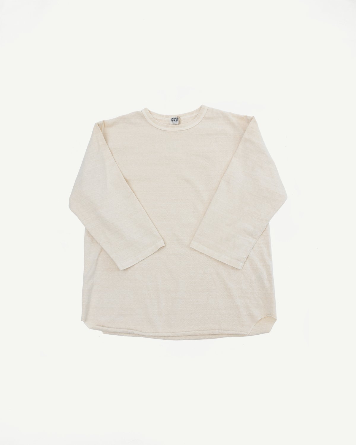 Flat lay front view of cream long sleeve crew neck tee with ribbed texture and brand tag