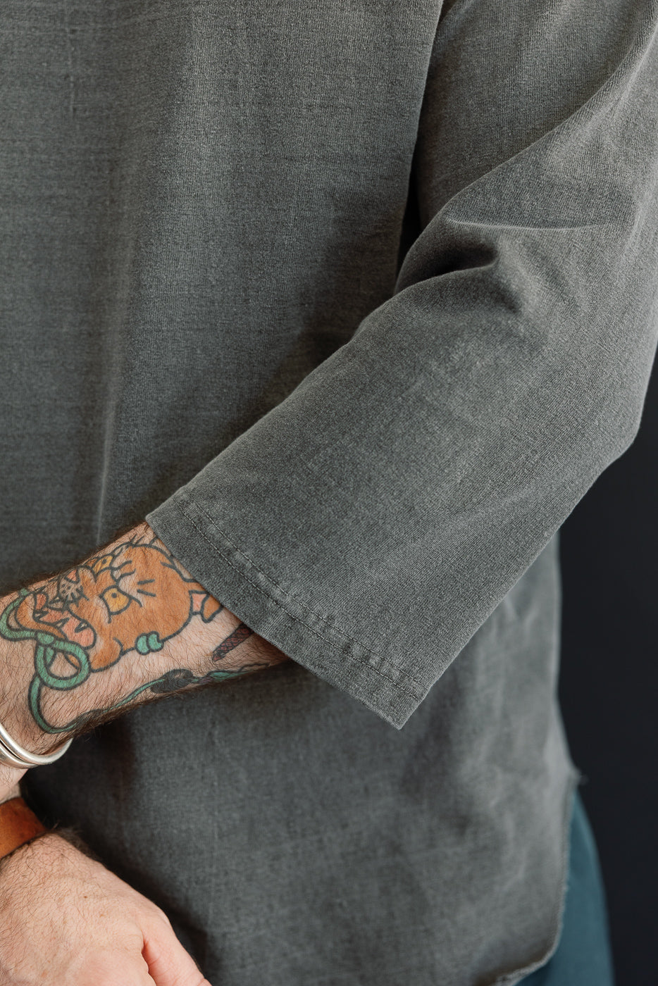 Close-up of male model's arm showing gray shirt sleeve hem and fabric texture