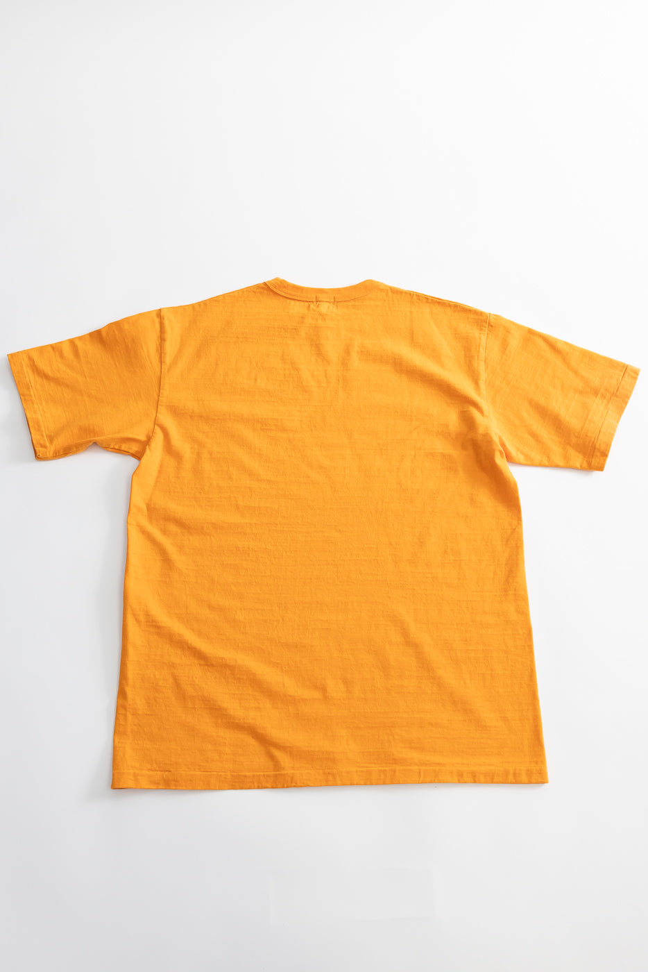 7.7oz - Fallen Cotton Midweight T-Shirt S/S - Fade Orange, showcasing its back view. The short-sleeve, crew-neck design emphasizes the natural slub texture of the recycled cotton jersey, laid flat on a white backdrop.