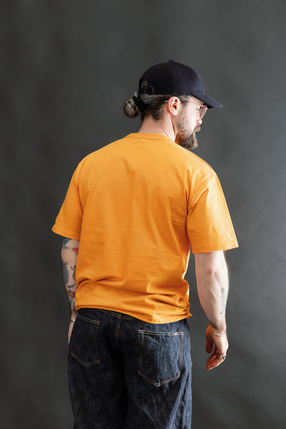 Model showcasing the 7.7oz Fallen Cotton Midweight T-Shirt S/S - Fade Orange, highlighting its recycled cotton slub texture and classic silhouette, ideal for layering and everyday wear.