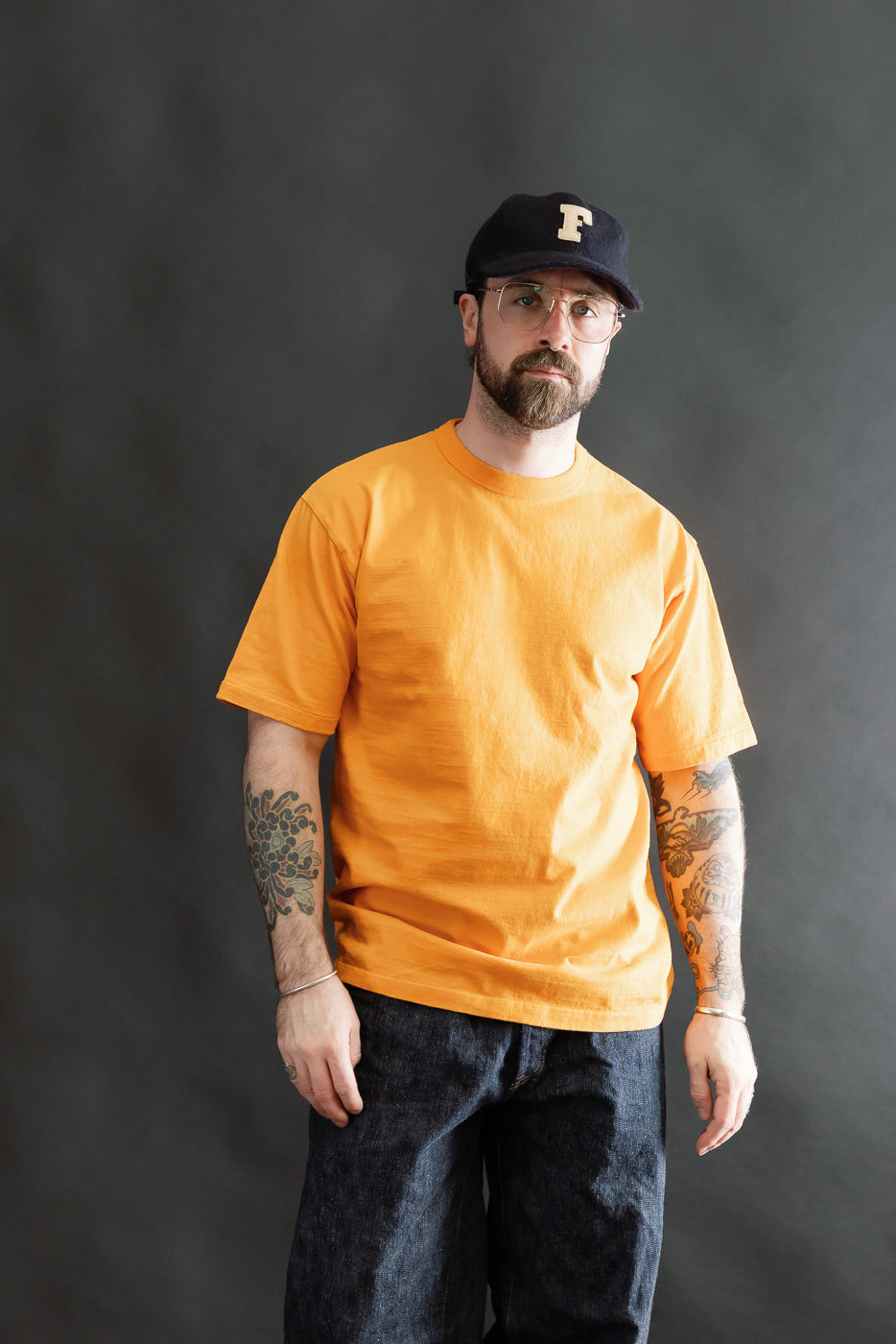 Model wearing the 7.7oz Fallen Cotton Midweight T-Shirt S/S in Fade Orange, showcasing its recycled cotton slub jersey texture, round body, and single-stitched hem, embodying Dant's premium menswear ethos.