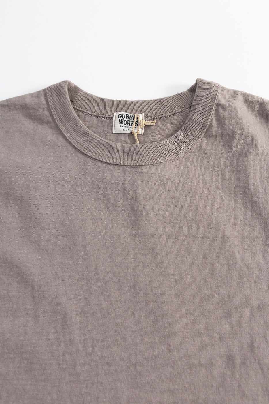 7.7oz - Fallen Cotton Midweight T-Shirt S/S - Grey, showcasing a flat-lay of the muted taupe crew-neck with ribbed collar, visible subtle slub texture, and a woven label reading DUBBI(ng) WORKS – MADE IN JAPAN – LARGE.