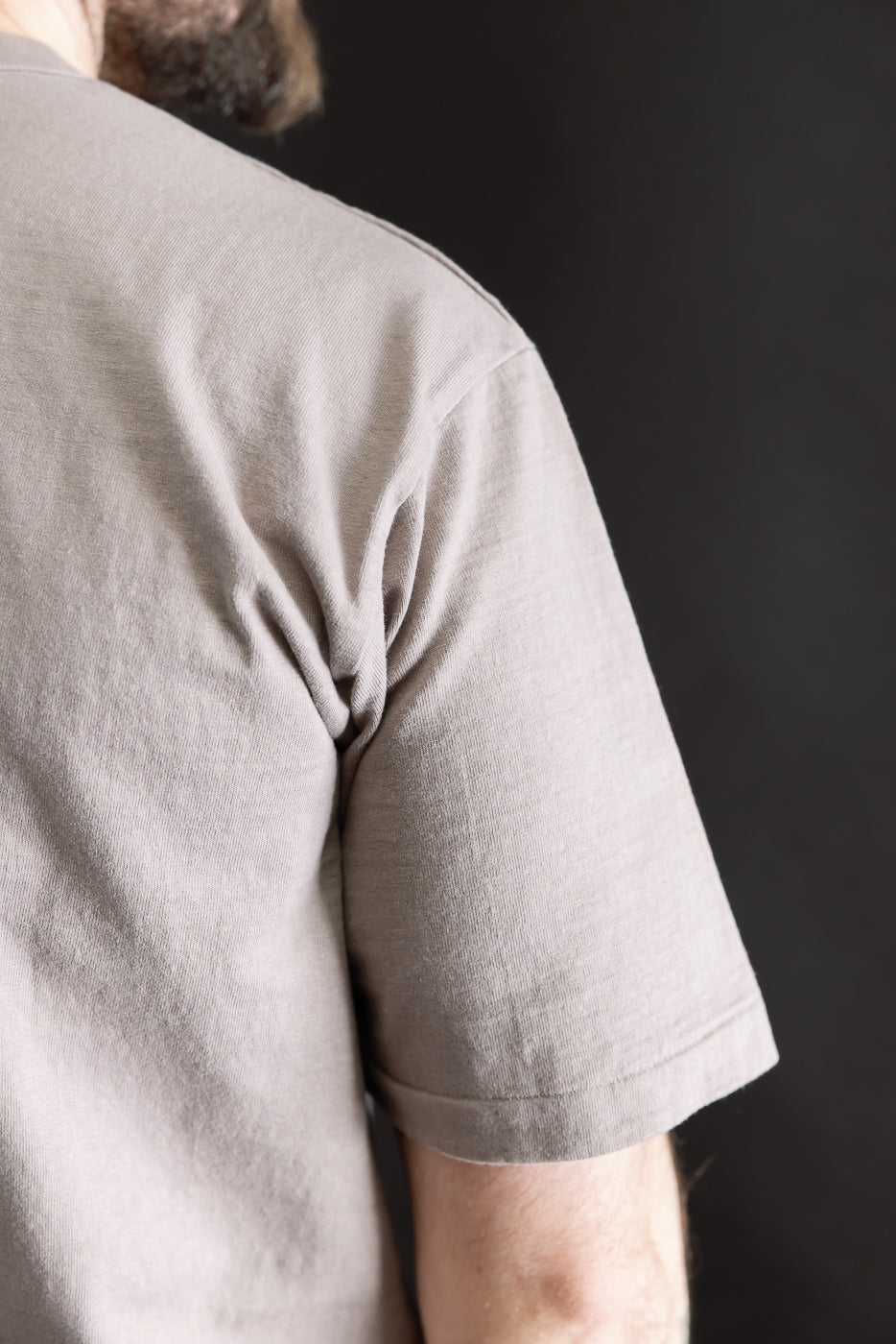 Close-up of a 7.7oz Fallen Cotton Midweight T-Shirt S/S in Grey, highlighting the textured recycled cotton slub fabric on the upper back and right arm, ideal for layering and everyday wear.