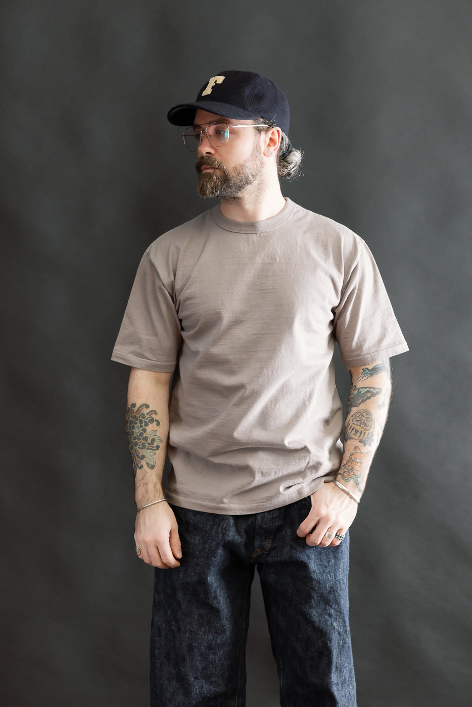 A man models the 7.7oz Fallen Cotton Midweight T-Shirt S/S - Grey, showcasing its recycled cotton slub jersey texture, short-sleeve design, and relaxed fit, embodying Dant's heritage-inspired menswear aesthetic.