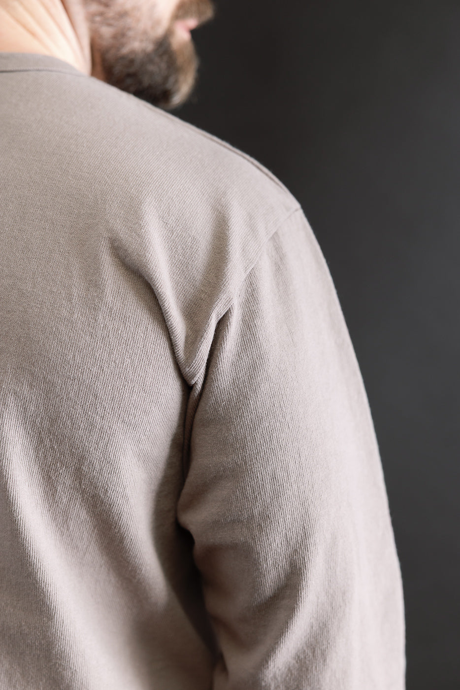 Close-up of heavyweight grey long sleeve tee on male model, showing back shoulder seam and fabric texture.