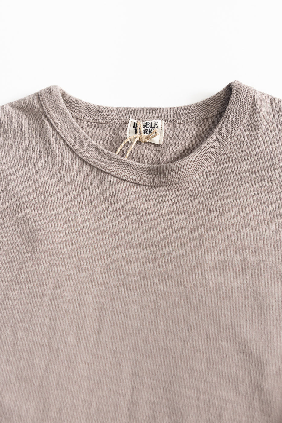 Close-up of grey heavyweight long sleeve tee front, showing ribbed crewneck and fabric texture.
