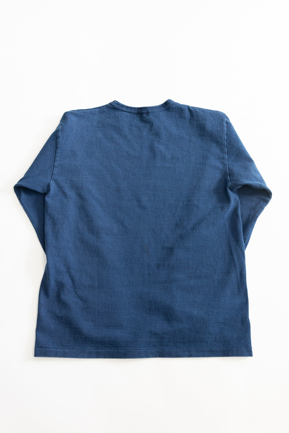 Flat lay of indigo-dyed heavyweight long sleeve tee, back view, showing fabric texture.