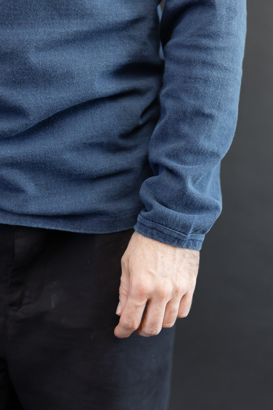 Close-up of male model's arm in navy corduroy long-sleeve, showing textured fabric and cuff detail