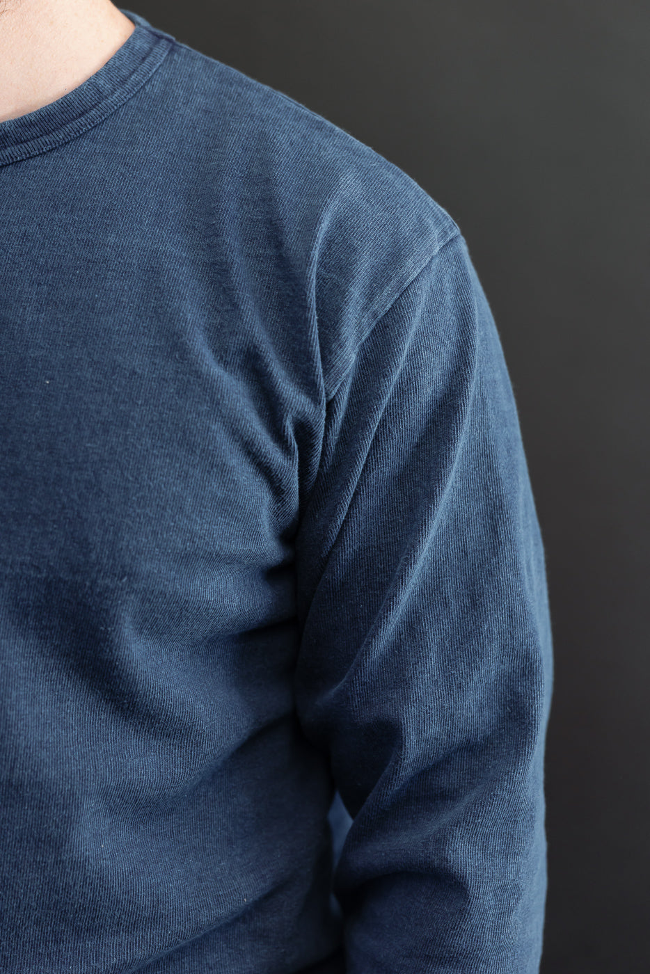 Close-up front view of navy corduroy long-sleeve shirt on male model, showing ribbed crew neck and sleeve texture