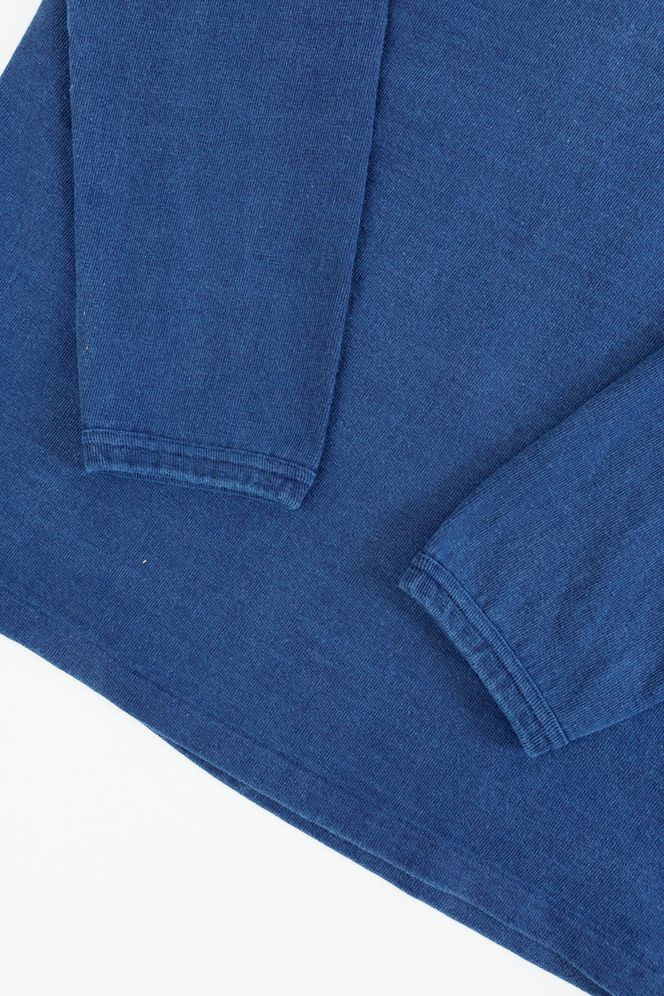 Close-up of blue long-sleeve shirt's front hem and sleeve cuffs, showcasing fabric texture and stitching details.