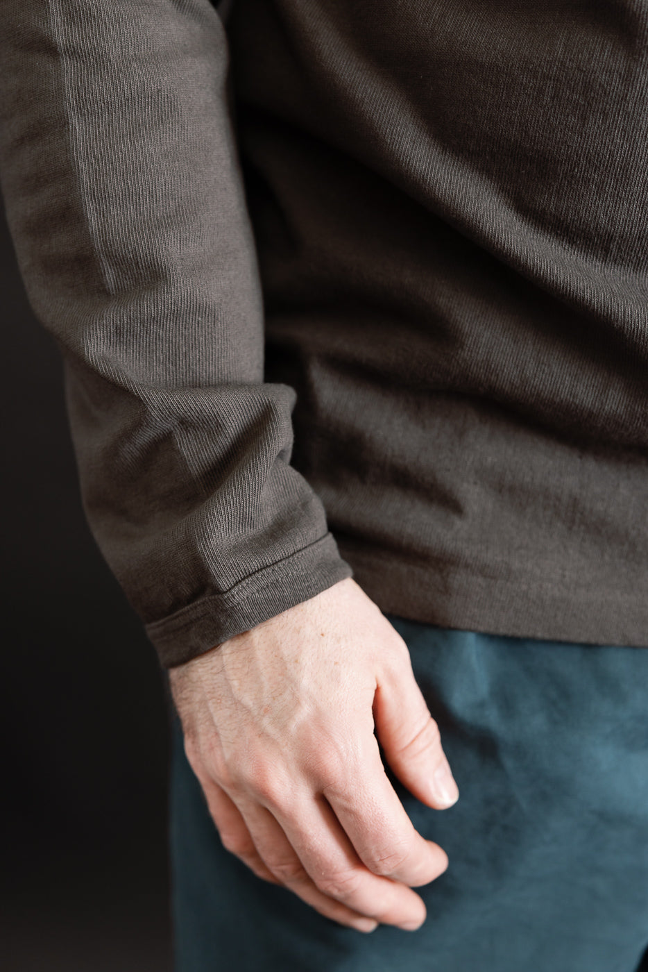 Close-up of male model's right sleeve cuff and hem, heavyweight long sleeve tee side view