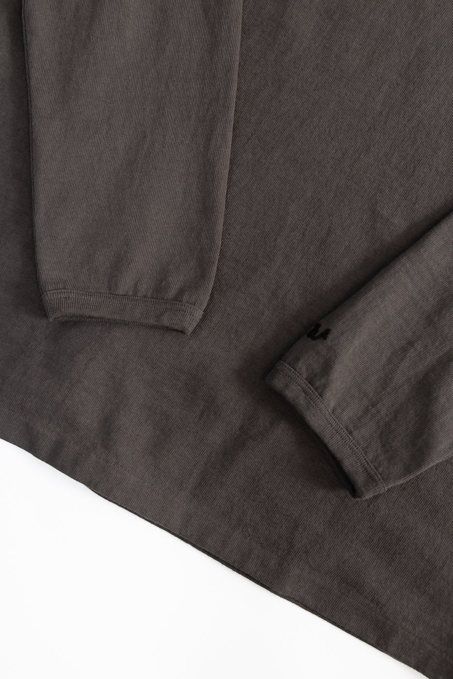 Close-up of heavyweight long sleeve tee front, showing sleeve cuffs and hem fabric texture.