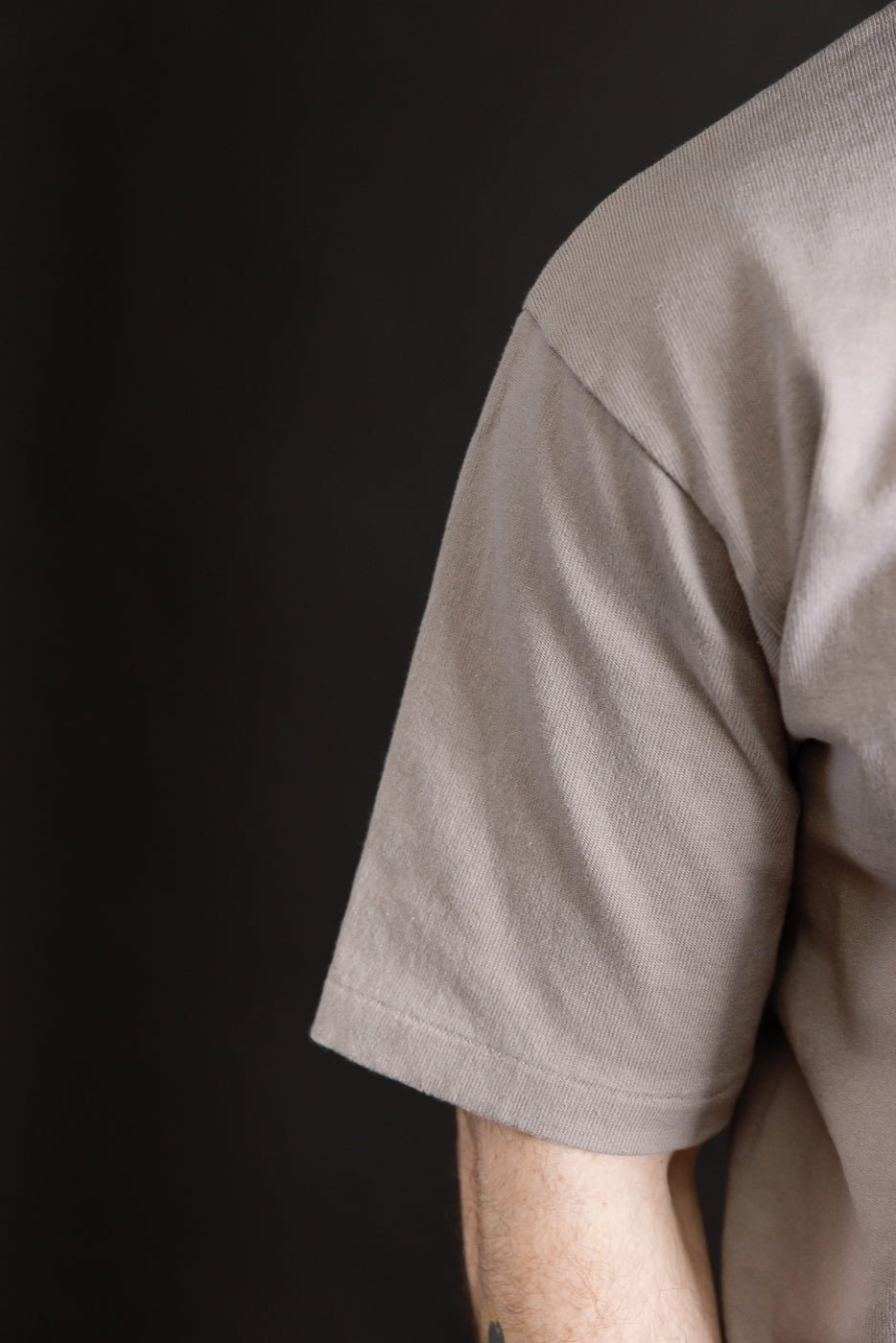 Close-up of the right sleeve and shoulder of a grey heavyweight men's t-shirt on a 5'9
