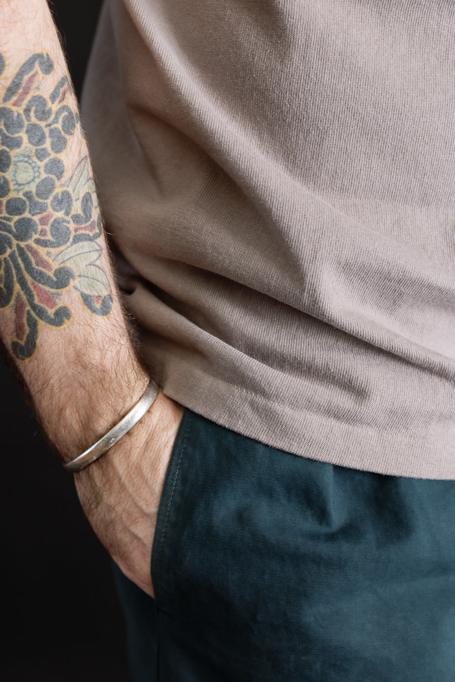 Close-up of male model’s right side in grey heavyweight tee, hem and fabric texture shown.