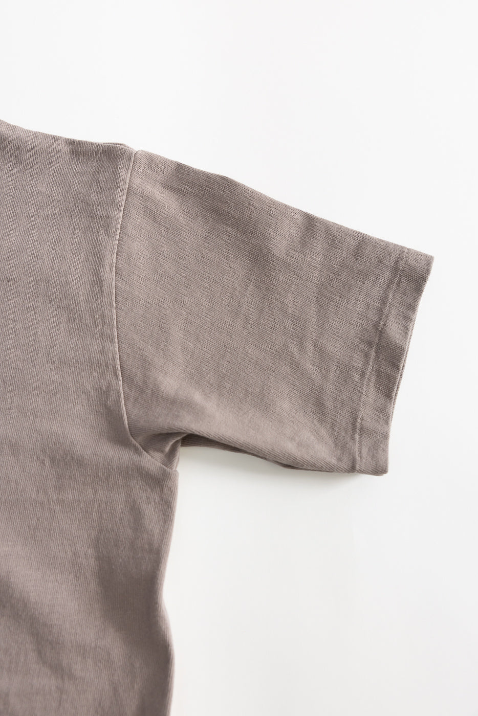 Close-up of grey heavyweight tee right sleeve, fabric texture detail, flat lay, front view