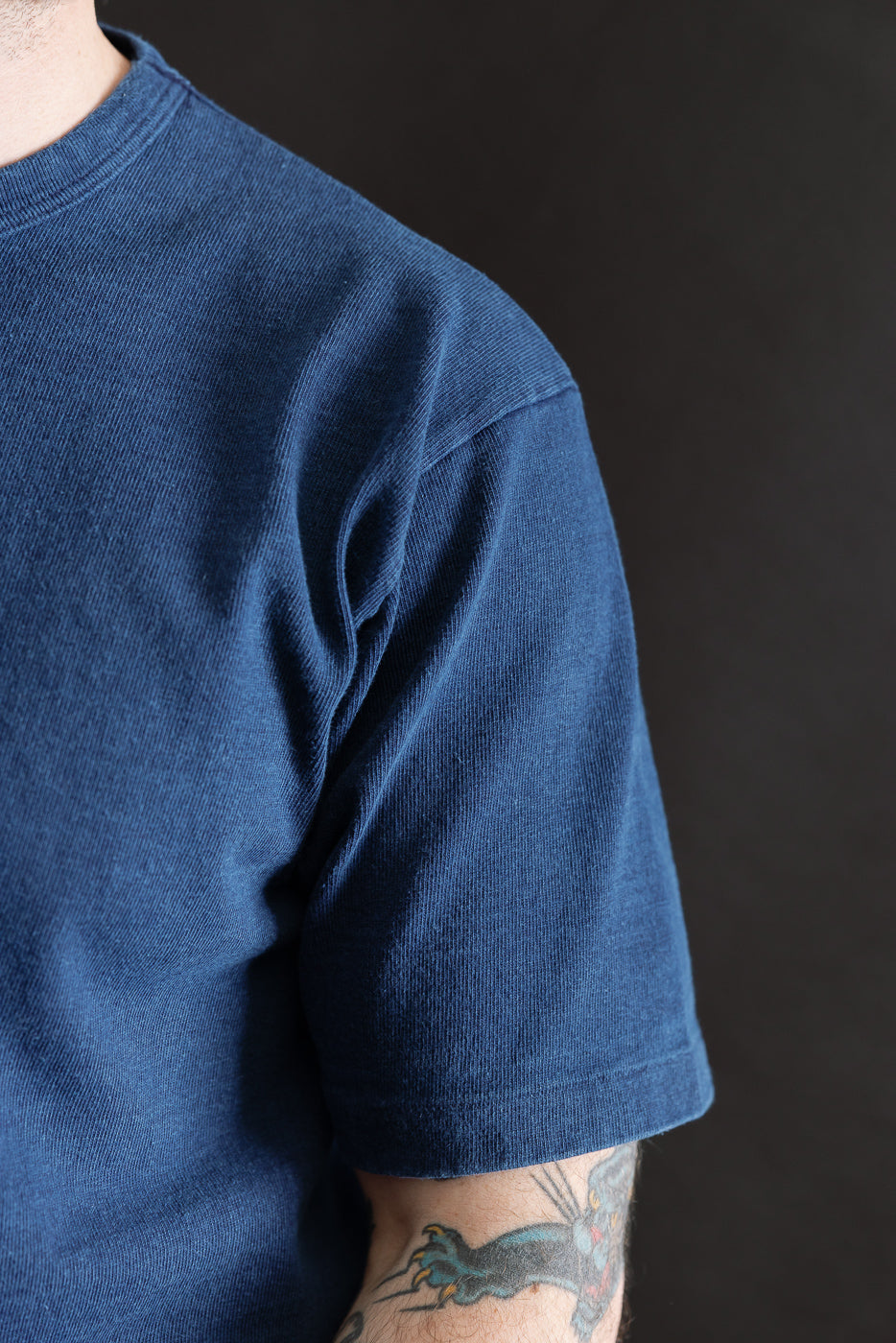 Close-up of male model's right side wearing indigo heavyweight tee showing sleeve and fabric texture