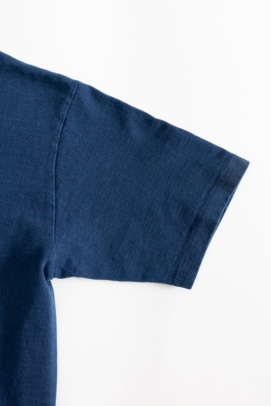 Close-up of indigo heavyweight tee, right sleeve detail, flat lay, showing fabric texture.