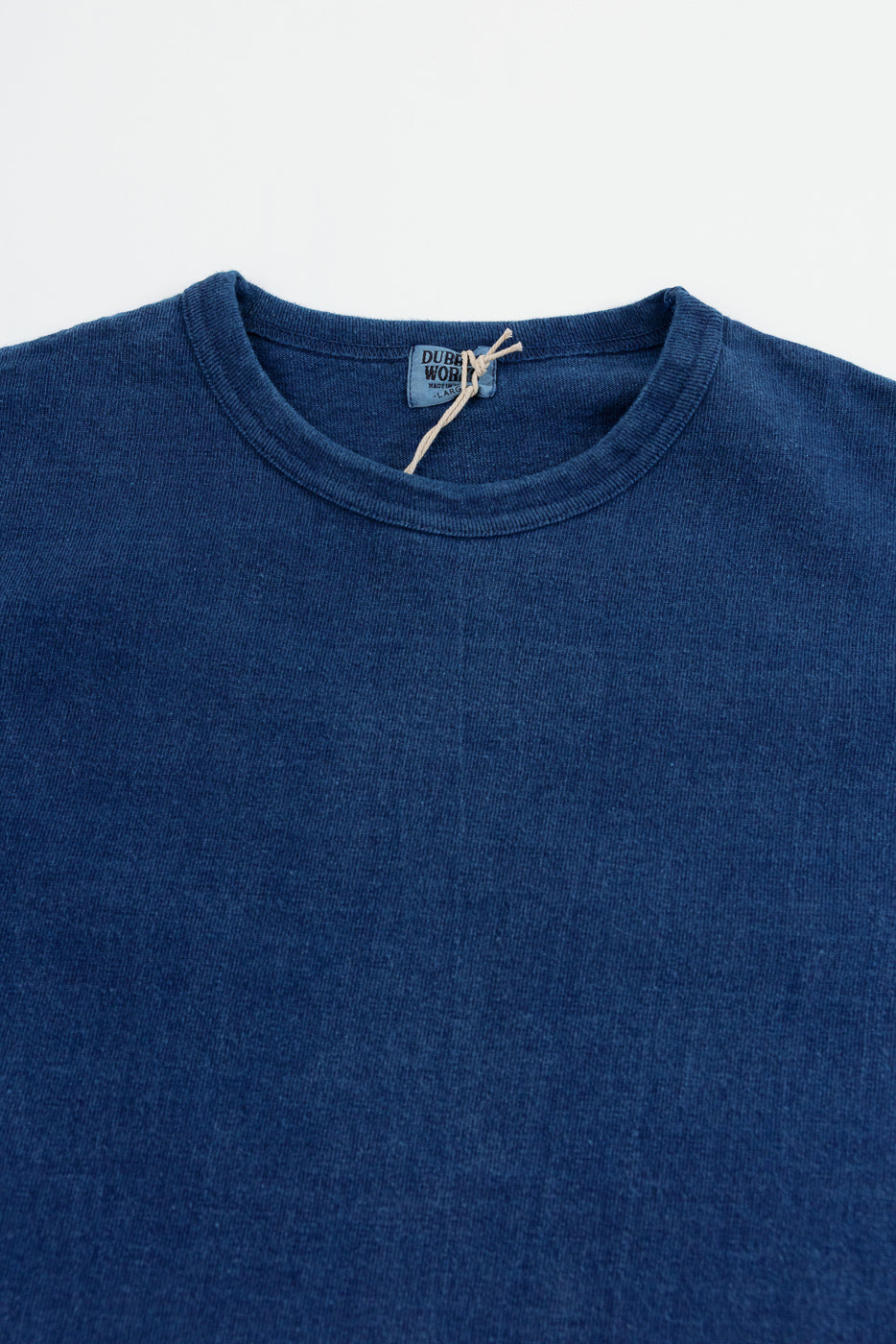 Close-up front view of navy blue crew neck tee, showcasing tag detail and soft fabric texture.