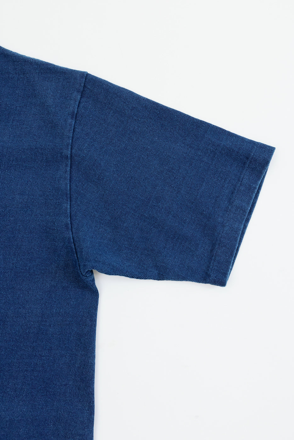 Close-up of navy blue t-shirt sleeve and shoulder seam, showing ribbed fabric texture and clean hem detail