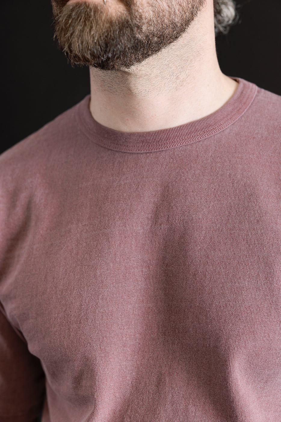 Close-up front view of heavyweight bordeaux pigment-dyed tee on male model, focusing on fabric texture and crew neck; model is 5'9