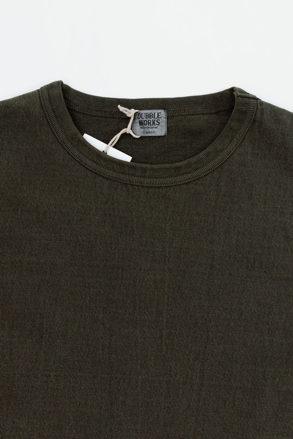 Close-up front view of olive green tee, ribbed crew neck, Dubble Works tag, fabric texture visible