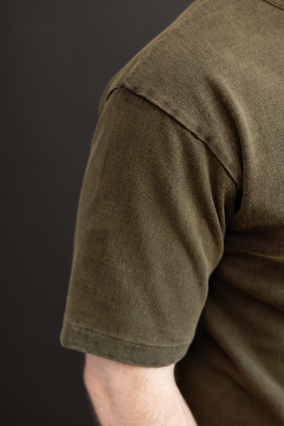 Close-up side view of olive green tee sleeve on male model, 5'9