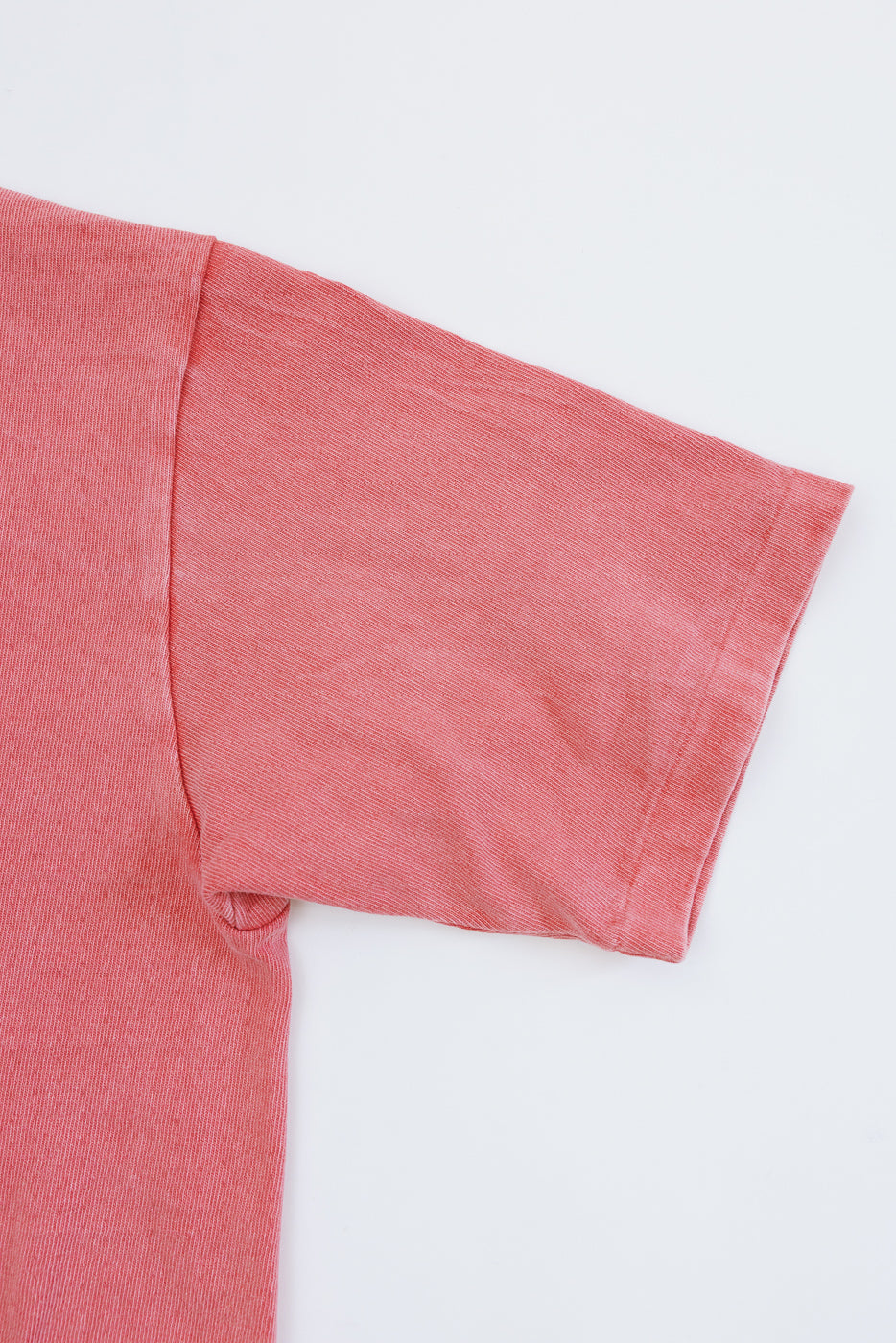 Close-up front view of coral short-sleeve tee, showing ribbed texture and sleeve hem detail