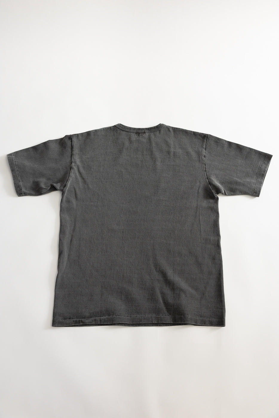 Flat lay of the back side of a pigment-dyed heavyweight black short sleeve tee.