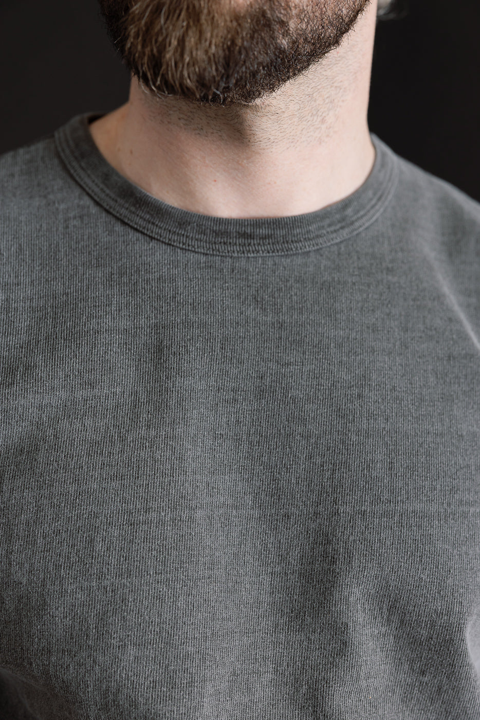 Close-up front view of male model wearing heavyweight pigment-dyed tee, showing collar and fabric texture.