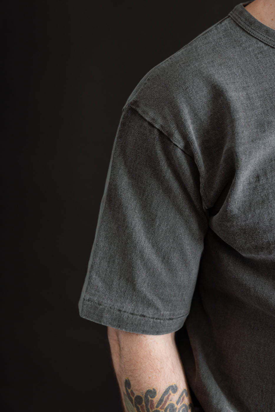 Close-up of right sleeve and shoulder of heavyweight sumikuro pigment dyed tee on male model, 5'9