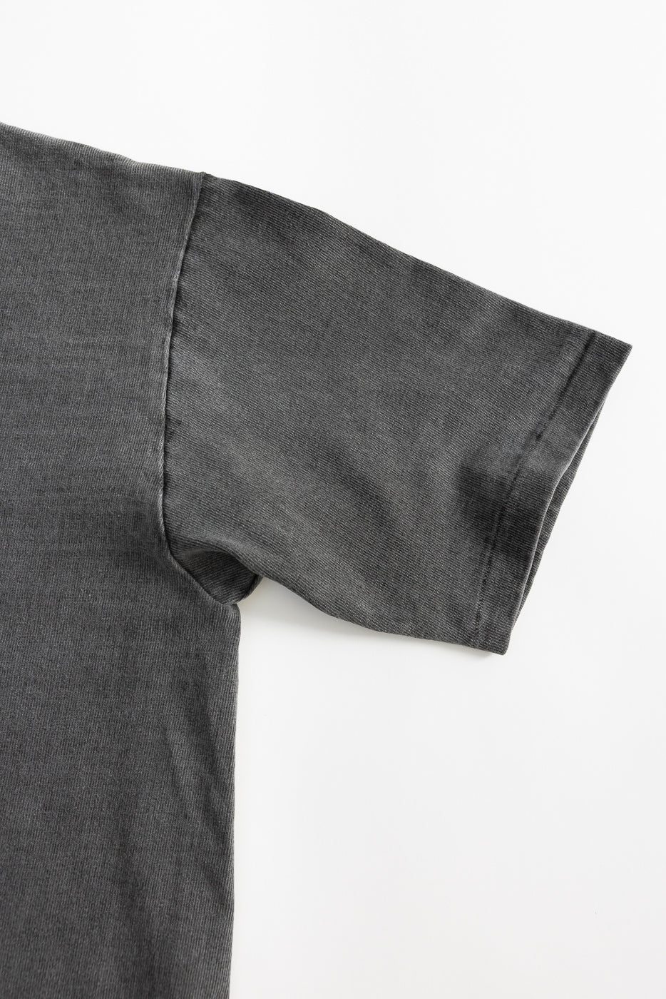Close-up of short sleeve and side seam, front left of heavyweight pigment-dyed grey tee.