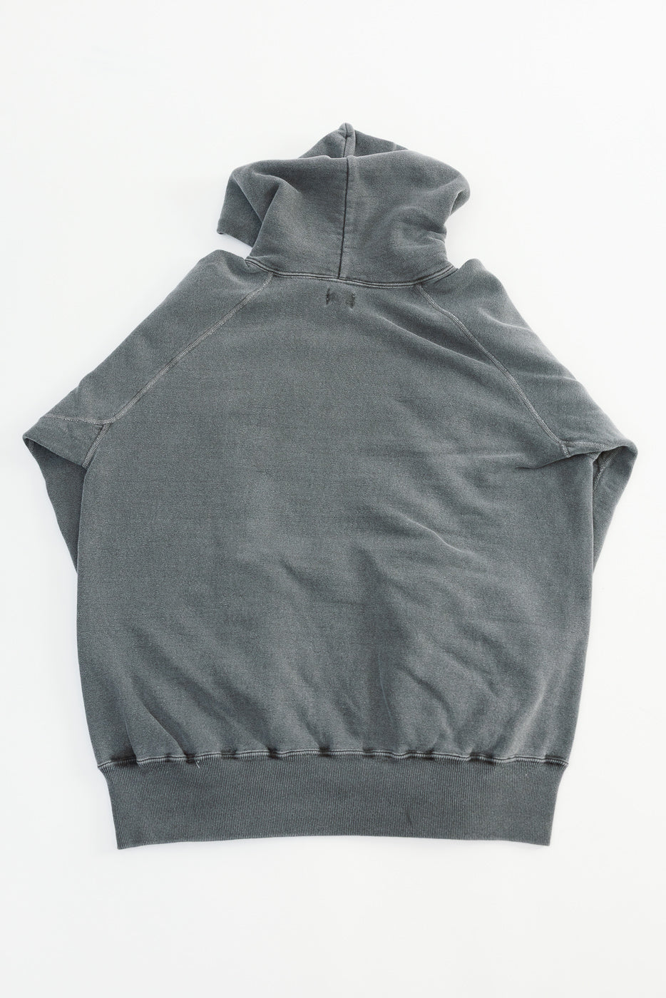 Flat lay of a faded black hoodie, back view showing hood, raglan sleeves, and ribbed hem.