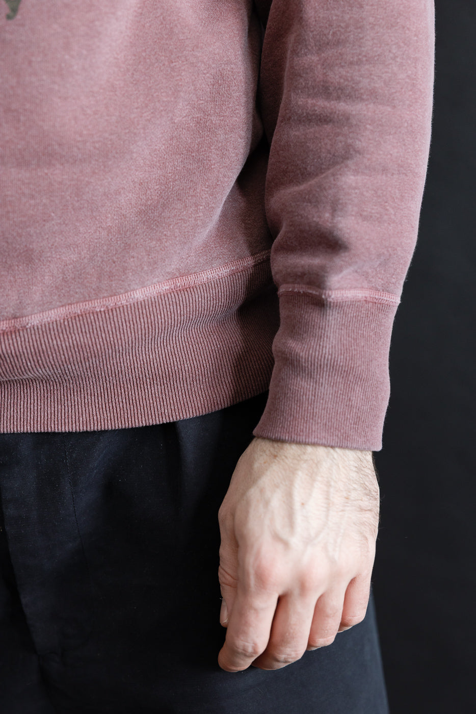 Close-up of male model’s right side, showing faded bordeaux sweatshirt sleeve and ribbed hem. Model is 5'9