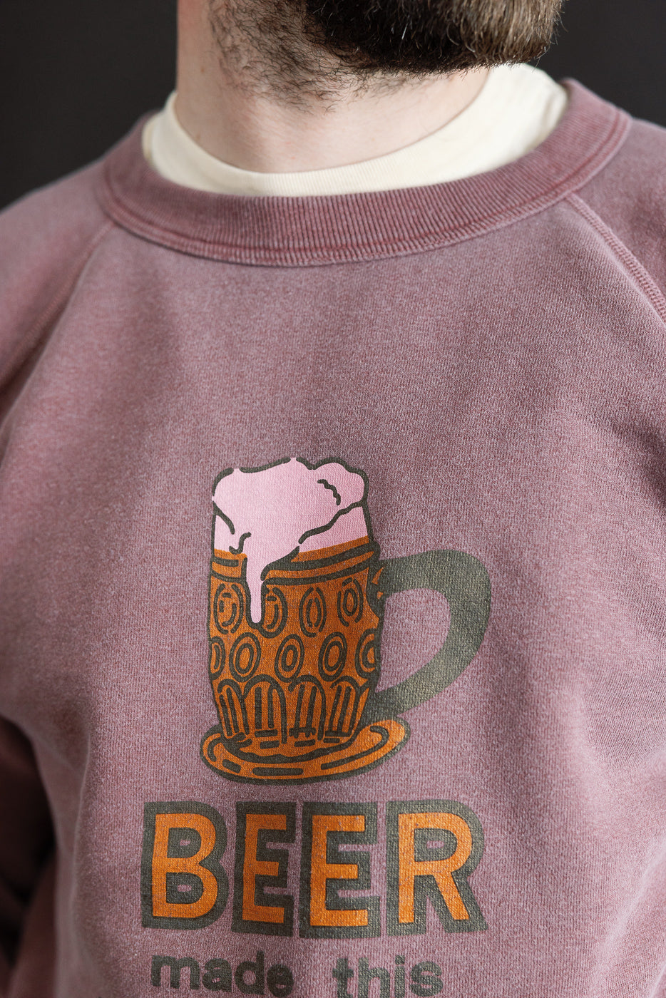 Close-up of front chest on men's bordeaux sweatshirt showing beer mug graphic, athletic male model, 5'9