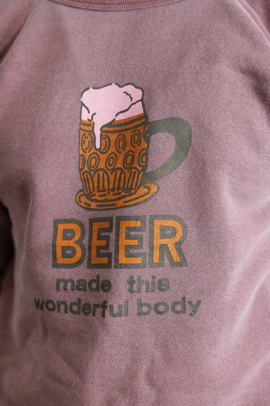 Close-up of front chest print on faded bordeaux sweatshirt, showing beer mug and slogan design.