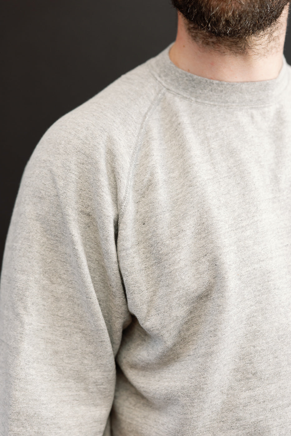 Close-up front view of heather gray crewneck sweatshirt on male model, showcasing fabric texture and fit