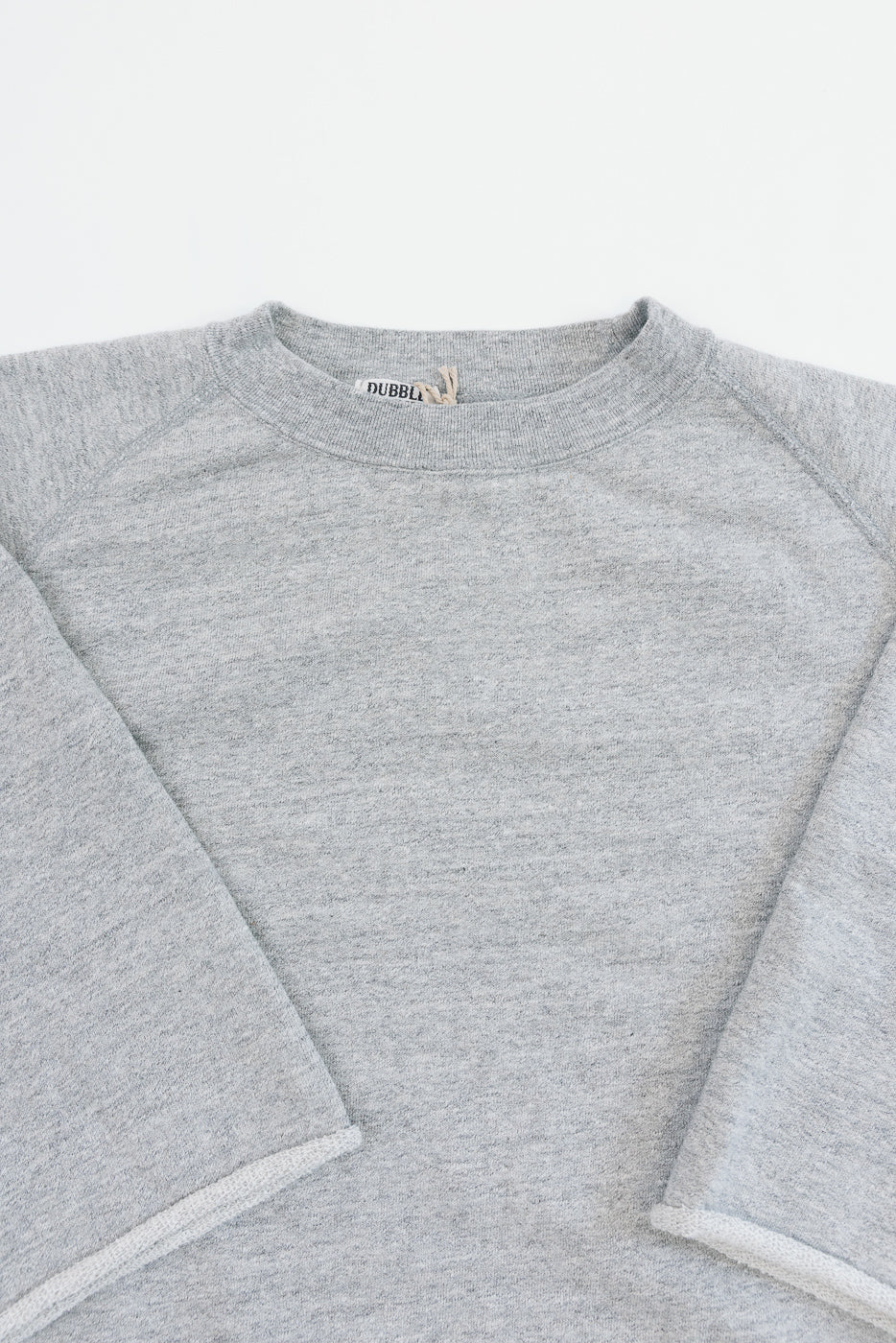 Close-up front view of heather gray crewneck sweatshirt with tag detail