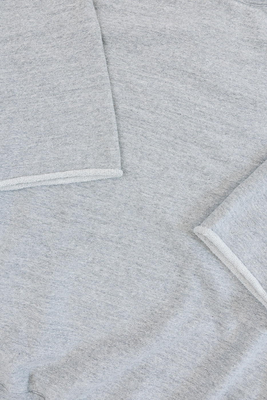 Close-up of heather grey sweatshirt front, showing soft texture and ribbed pocket trim detail.